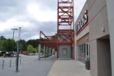 Thumbnail for Exterior view of a bookstore entrance with red metal framework and a cloudy sky overhead.
