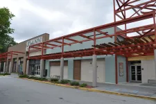 Thumbnail for Exterior view of a shopping center with Jo-Ann fabric store and covered walkway with red metal framework.