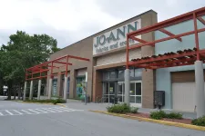 Thumbnail for Exterior view of JOANN fabrics and crafts store with brick facade and red pergola on a cloudy day
