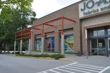 Thumbnail for Exterior view of Jo-Ann Fabrics and Crafts store with brick facade and red metal awning structure.