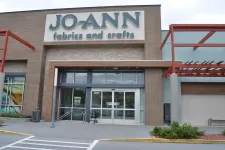 Thumbnail for Facade of Jo-Ann Fabrics and Crafts store with glass entrance and exterior signage on a cloudy day