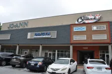 Thumbnail for Shopping plaza exterior with storefronts including JOANN, OB/GYN, Kumon, and parking lot with cars in front.