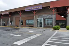 Thumbnail for Empty parking lot outside a shopping plaza featuring Louisiana Bistreaux and Smoothie King storefronts under an overcast sky