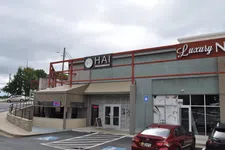 Thumbnail for Exterior view of a nail salon with signage, parking spaces, and a red car under a cloudy sky.