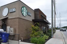 Thumbnail for Exterior view of a Starbucks coffee shop with drive-thru signs on a cloudy day.