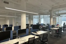 Thumbnail for Modern open office with rows of desks, computer monitors, office chairs, and white columns under bright lighting.