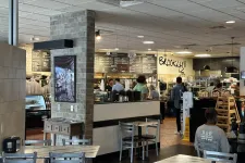 Thumbnail for Interior of a casual café with customers ordering at counter, tables and chairs, and a visible menu board.