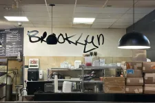Thumbnail for Interior of a Brooklyn restaurant with shelves, stacked boxes, pendant lights, and handwritten wall text.