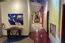 Thumbnail for Colorful hallway with polished floors, artwork on the walls, and a wooden table with decorative items