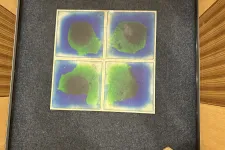 Thumbnail for Four abstract watercolor paintings with green and blue hues arranged in a square on a gray carpeted floor.
