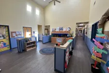 Thumbnail for Bright and spacious childcare center hallway with colorful decorations, aquarium, and directional signposts.