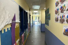 Thumbnail for Bright school hallway decorated with student artwork on walls and a view to a glass exit door at the end.