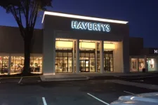 Thumbnail for Havertys furniture store entrance illuminated at night with empty parking lot and tree in foreground