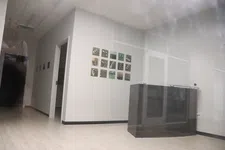 Thumbnail for Modern office hallway with light wood flooring, white walls, and a dark reception desk under soft ceiling lights