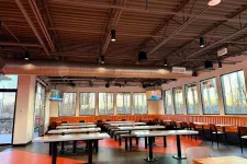 Thumbnail for Spacious restaurant dining area with orange booths, wooden tables, black chairs, and large windows with outdoor views.