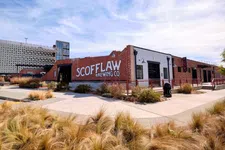 Thumbnail for Scofflaw Brewing Co. brick building with outdoor landscaping and clear sky in an urban setting.