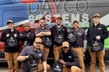 Thumbnail for Dayco Systems team of technicians posing with branded bags in front of a company van with ladder on top.