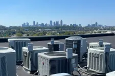Thumbnail for Multiple rooftop HVAC units installed on a building roof with the city skyline under clear blue sky