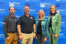 Thumbnail for Four professionals standing in front of Rome Floyd Chamber backdrop during an event or meeting.
