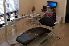 Thumbnail for Modern dental clinic room with a reclining patient chair, overhead light, computer, and medical equipment.