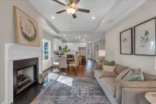 Thumbnail for Bright open living room with fireplace, ceiling fan, gray sofa, dining table, and hardwood flooring under natural light
