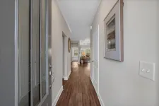 Thumbnail for View of a modern hallway with wood flooring, neutral walls, a wall painting, and a glimpse into a living room area