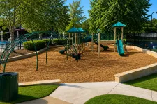 Thumbnail for Empty playground with slides, climbing structures, and green trees on a sunny day with clear skies.