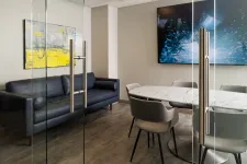 Thumbnail for Modern office meeting room with glass doors, marble table, grey chairs, black sofa, and abstract wall art.