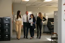 Thumbnail for Four diverse professionals walking through an office corridor reviewing a document together during work hours.