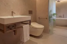 Thumbnail for Modern bathroom with wall-mounted sink, sleek toilet, towel rack, and bathtub behind frosted glass door.