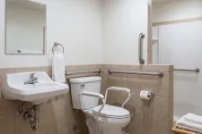 Thumbnail for Accessible bathroom with wall-mounted sink, supportive handrails, raised toilet with armrests, and a shower area with grab bars.