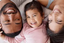 Thumbnail for Happy family of three lying down together smiling, showing close bond and joyful moments