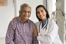 Thumbnail for Smiling female doctor with stethoscope embraces senior male patient in medical office with skeleton model.