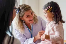 Thumbnail for Smiling female doctor interacts with young girl patient during a friendly medical check-up in clinic.