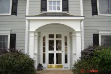 Thumbnail for a white house with a large front door and bushes in front