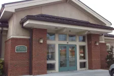 Thumbnail for Entrance of Advanced Dermatology & Skin Surgery clinic with brick pillars and teal double doors under a gabled roof.