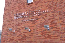 Thumbnail for Brick building exterior displaying Proliance Surgeons and Evergreen Orthopedic Center signage with outdoor lights.