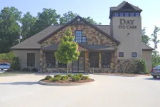 Thumbnail for Modern stone and stucco eye care clinic building with a small tree and roundabout in front under clear sky