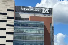 Thumbnail for Kellogg Eye Center building with University of Michigan logo under blue sky and white clouds.