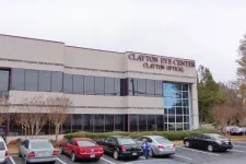 Thumbnail for Clayton Eye Center building with parked cars and trees in front under a cloudy sky.