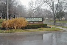 Thumbnail for Sign for KU Eye Center and Prudential Kansas City Realty on a rainy day with bare trees and wet pavement.