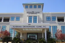 Thumbnail for Front view of Alabama Orthopaedic Clinic building with glass windows and green landscaping under clear sky