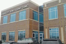 Thumbnail for Exterior view of Kansas City Bone & Joint Clinic building with parked cars in front on a cloudy day