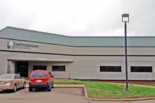 Thumbnail for Orthopaedic Associates medical office building with parked cars and green roof under cloudy sky