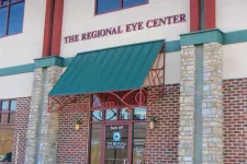 Thumbnail for Entrance of The Regional Eye Center with green awning and stone brick facade on a sunny day