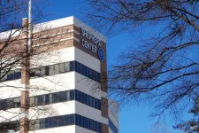 Thumbnail for Shepherd Center medical building with blue sky and bare tree branches in foreground.