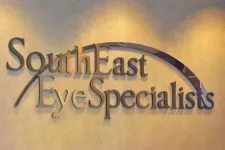 Thumbnail for SouthEast Eye Specialists sign with arched design on beige wall under soft lighting.