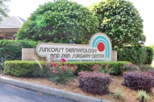 Thumbnail for Sign for Suncoast Dermatology and Skin Surgery Center surrounded by bushes and flowers at roadside.