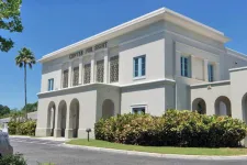 Thumbnail for White two-story building labeled Center for Sight with arched windows and greenery under clear blue sky.