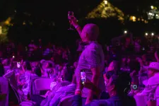 Thumbnail for a person sitting on a stage in front of a crowd